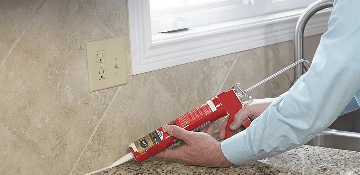 Handyman applying caulk along a kitchen backsplash and countertop seam in Honolulu, HI